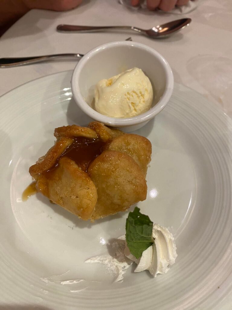 A pastry on a white plate with ice cream.