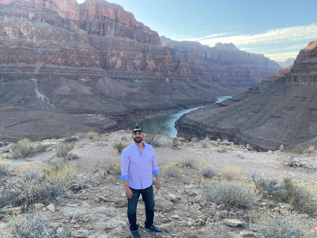 a man stands in front of a river in the Grand Canyon on a Las Vegas helicopter tour