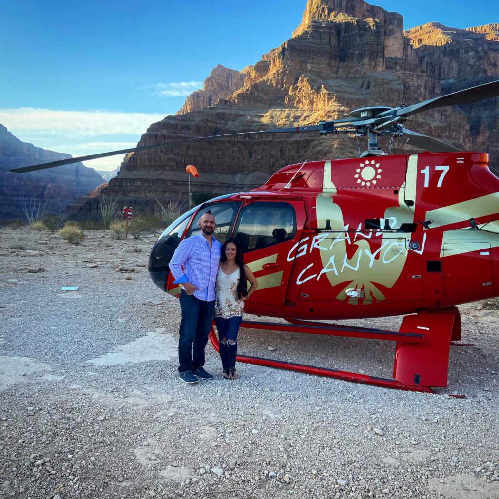 a couple stands in front of a helicopter in the during a Grand Canyon Las Vegas Tour