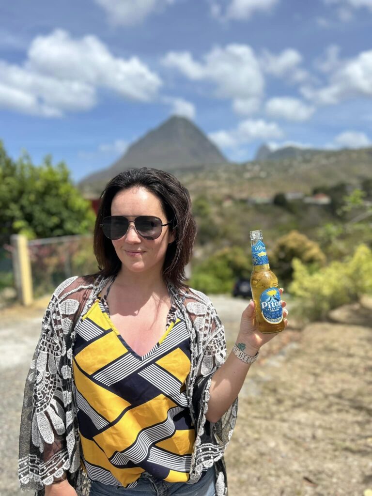 a woman holding a Piton beer on St. Lucia Piton tours