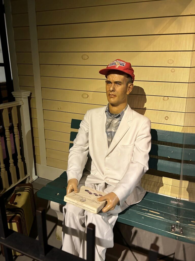 a Forrest Gump wax sculpture sitting on a bench