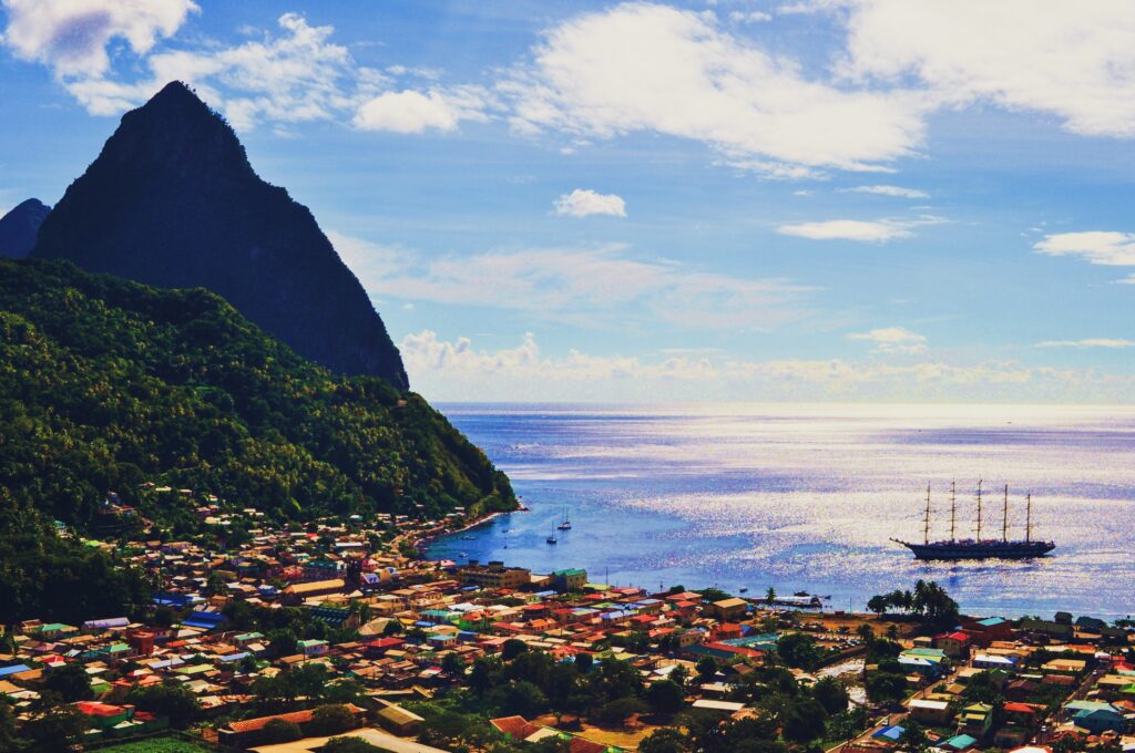 The Piton mountain and a sprawling coastal town, with ship in the water.