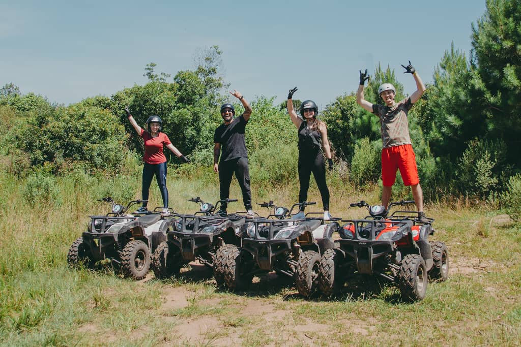 4 people standing on ATVs