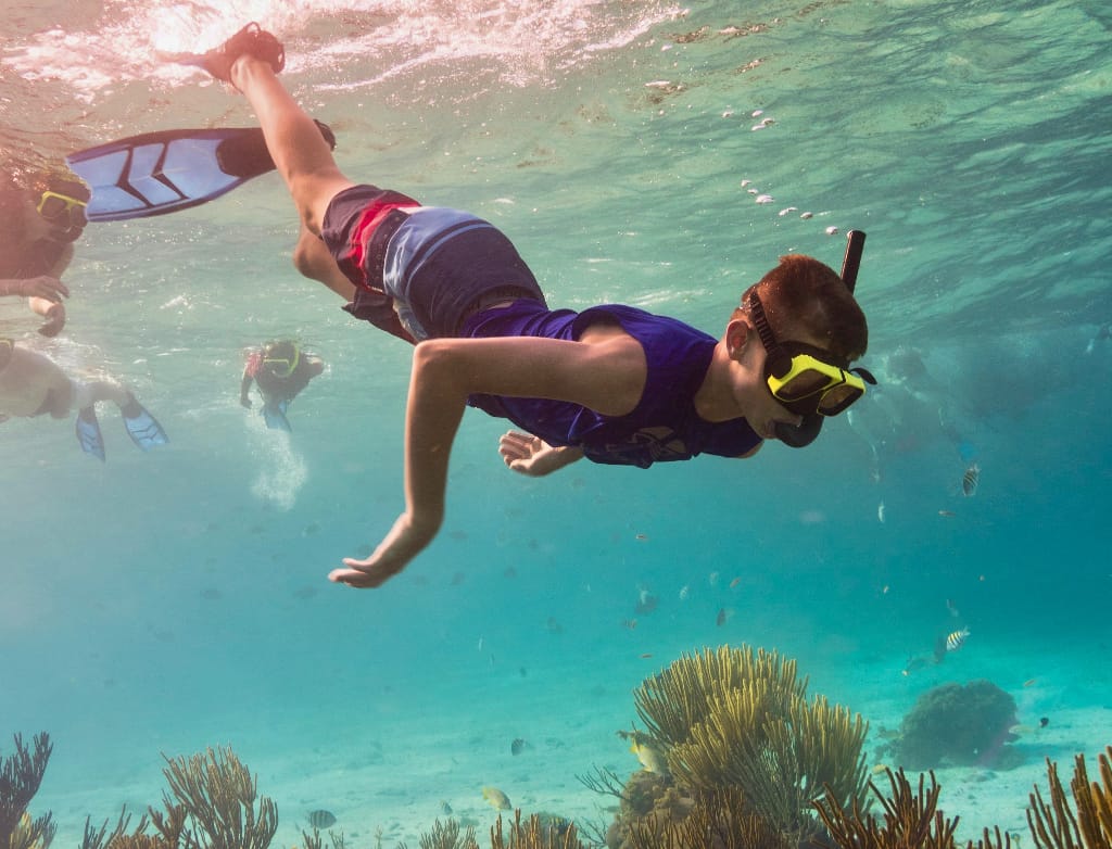 a boy snorkeling in clear blue water
