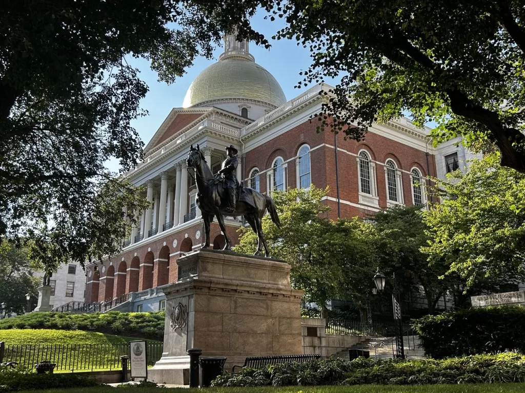 The State House behind a statue of a man on a horse.