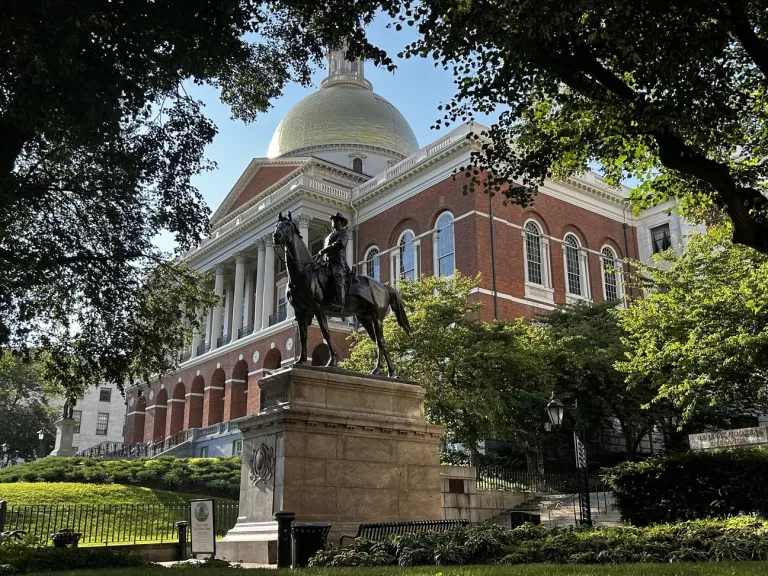The State House behind a statue of a man on a horse.