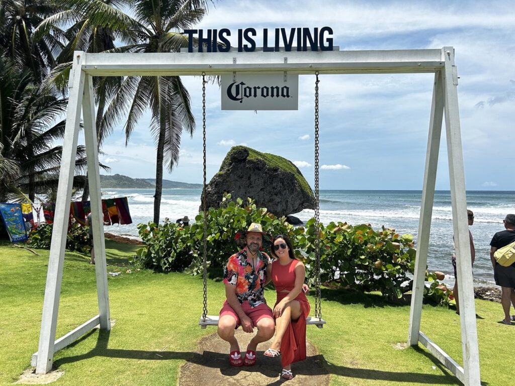 a couple sits on a giant swing with the words "this is living" above it.