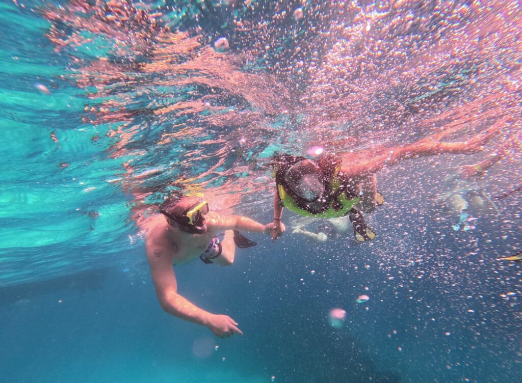 two people snorkel under the water