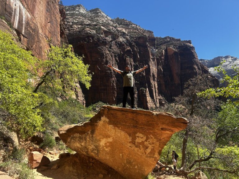 A man on a giant boulder in Zion National Park